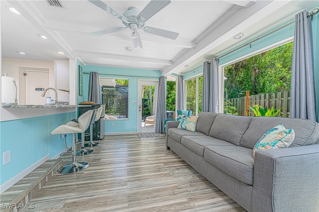 living room featuring ceiling fan, light wood-type flooring, and beam ceiling