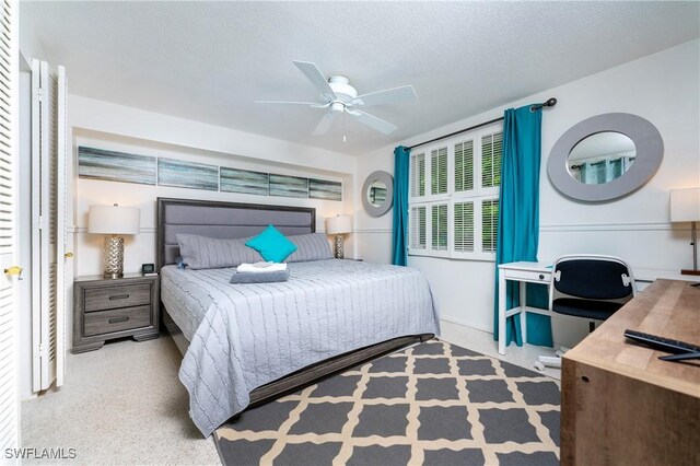 carpeted bedroom featuring ceiling fan and a textured ceiling