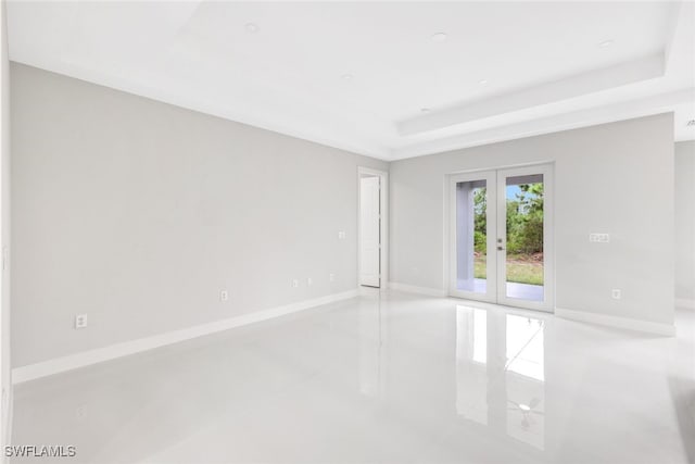 unfurnished room featuring light tile patterned floors, a tray ceiling, and french doors