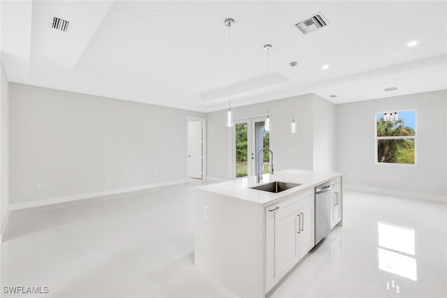 kitchen featuring sink, stainless steel dishwasher, a tray ceiling, a kitchen island with sink, and white cabinets