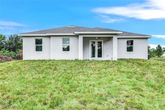 rear view of property with ceiling fan and a yard