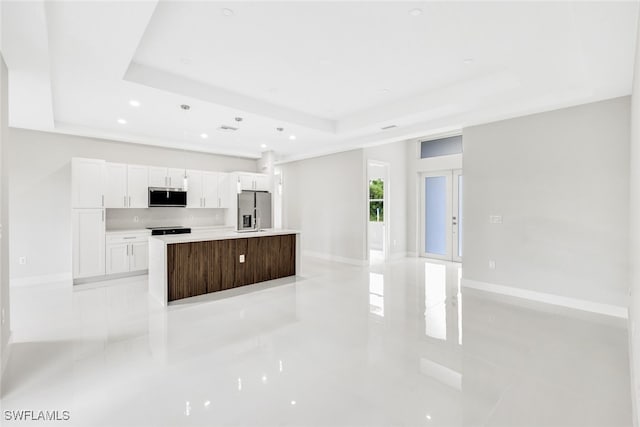 kitchen with white cabinets, appliances with stainless steel finishes, a raised ceiling, and a kitchen island