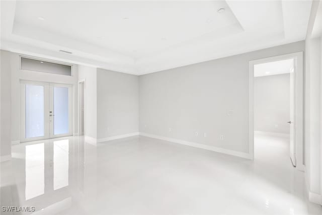 unfurnished room featuring a tray ceiling and french doors