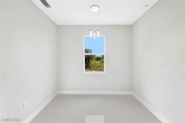 empty room featuring concrete floors and a notable chandelier