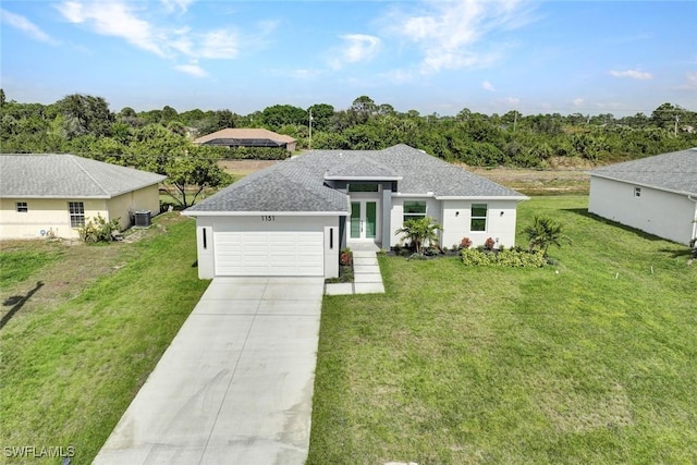 view of front of property with french doors, an attached garage, a shingled roof, and a front yard