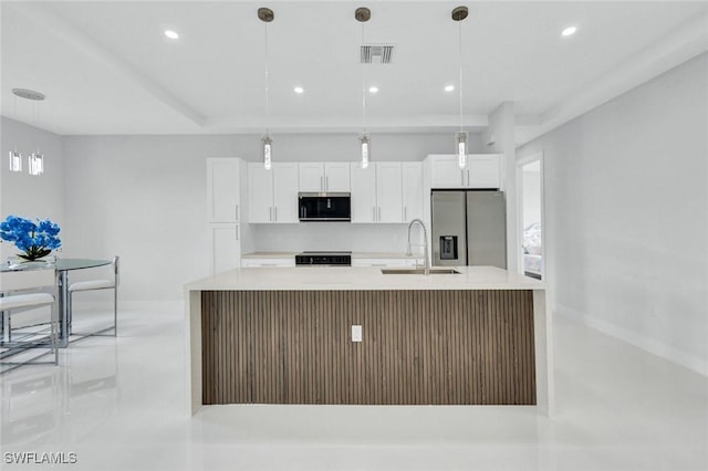kitchen featuring a sink, an island with sink, stainless steel appliances, white cabinetry, and visible vents