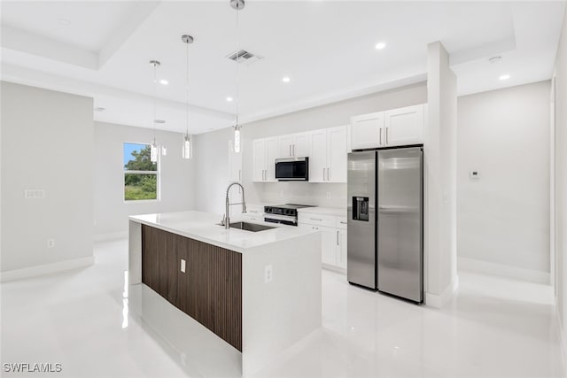 kitchen featuring visible vents, a center island with sink, white cabinetry, a sink, and stainless steel appliances