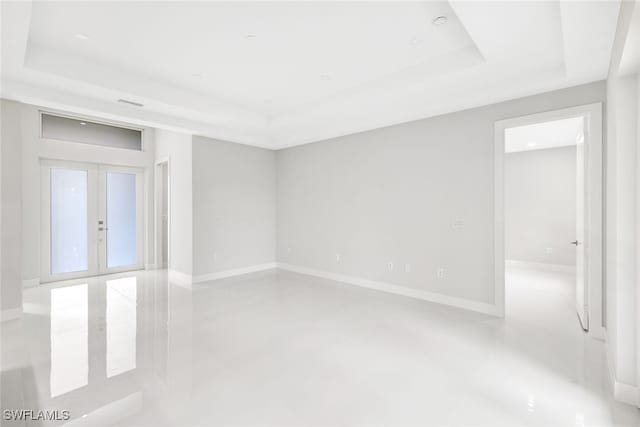1155 Ermine St E, Lehigh Acres, FL 33974 - empty room featuring a tray ceiling, finished concrete flooring, and french doors