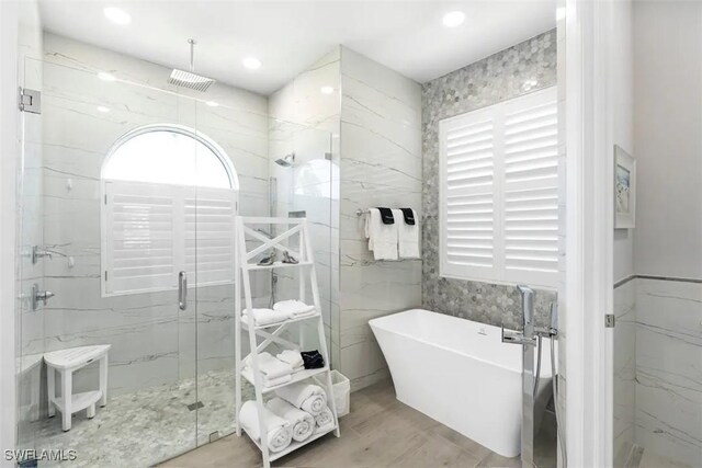 bathroom with tile walls, hardwood / wood-style flooring, and separate shower and tub