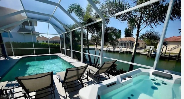 view of pool with glass enclosure, a water view, and a patio area