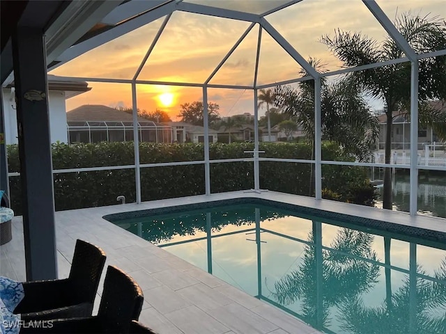 pool at dusk featuring glass enclosure and a patio area