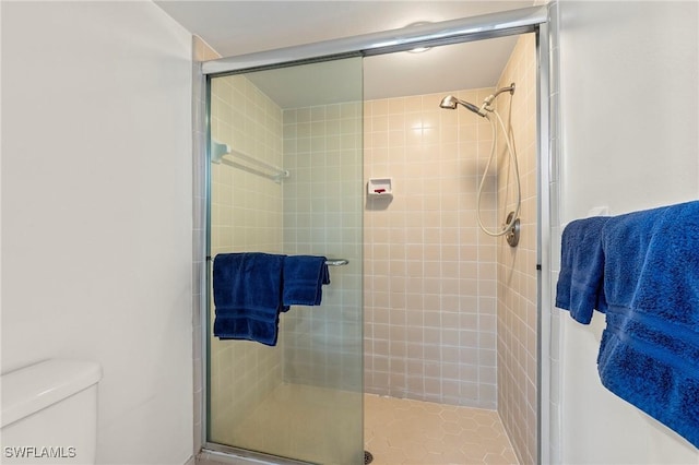 bathroom featuring toilet and a shower with door