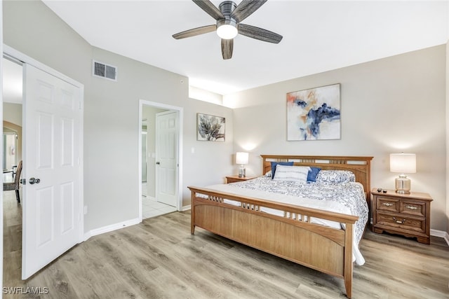 bedroom with light hardwood / wood-style floors, ensuite bathroom, and ceiling fan