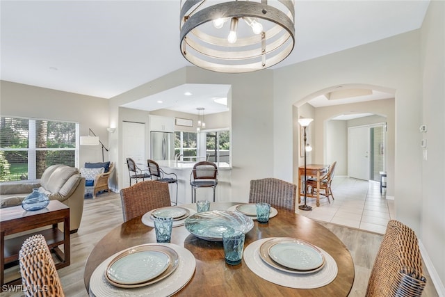 dining area with a raised ceiling, light hardwood / wood-style floors, and a notable chandelier