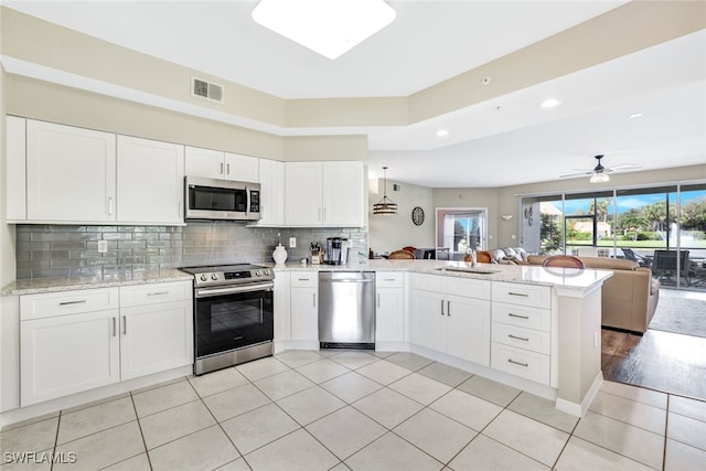 kitchen with white cabinets, kitchen peninsula, appliances with stainless steel finishes, and ceiling fan