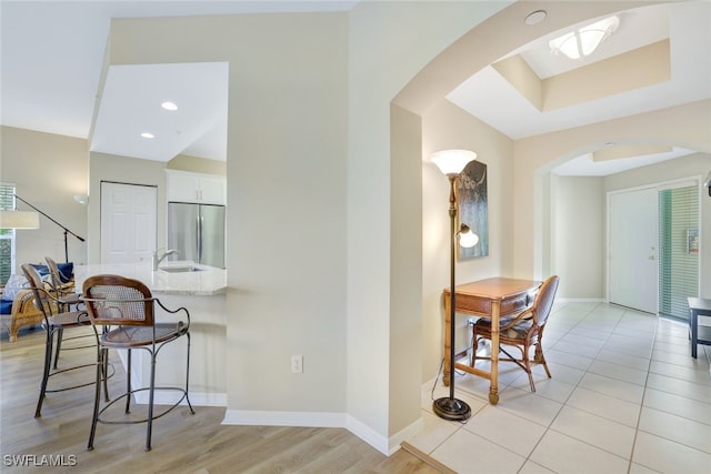 kitchen featuring light wood-type flooring, a breakfast bar area, white cabinetry, kitchen peninsula, and stainless steel fridge