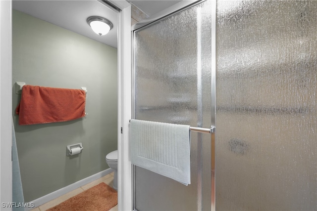 bathroom with a shower with shower door, toilet, and tile patterned floors