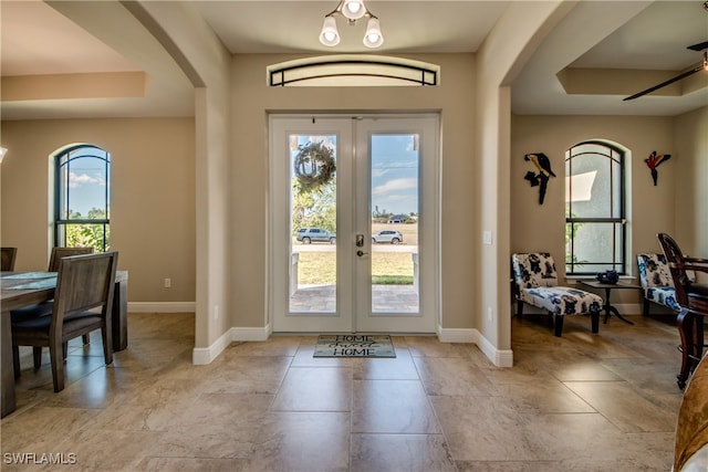 foyer featuring a tray ceiling, ceiling fan, french doors, and a wealth of natural light