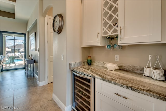 bar featuring light stone countertops, beverage cooler, white cabinetry, and light tile patterned floors