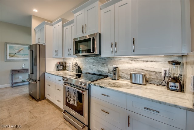 kitchen featuring appliances with stainless steel finishes, decorative backsplash, light stone countertops, and white cabinets