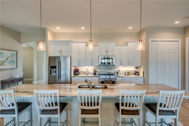 kitchen featuring appliances with stainless steel finishes, white cabinetry, pendant lighting, a large island, and sink