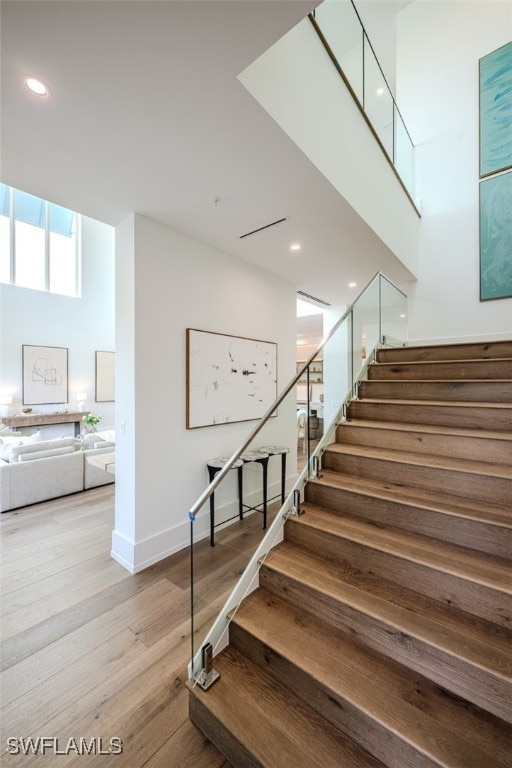 staircase with a high ceiling and hardwood / wood-style flooring