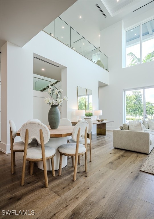 dining area featuring wood-type flooring and a high ceiling