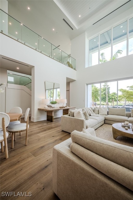 living room with a healthy amount of sunlight, a towering ceiling, and hardwood / wood-style floors