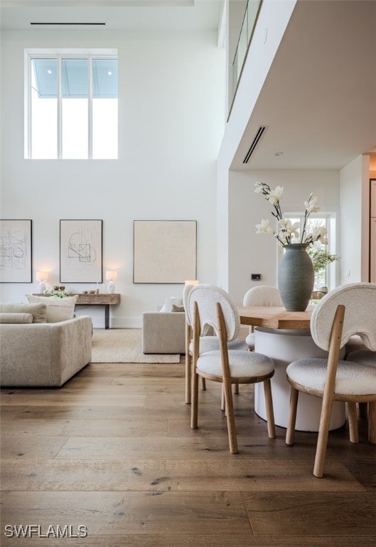 dining area with a high ceiling, hardwood / wood-style floors, and plenty of natural light