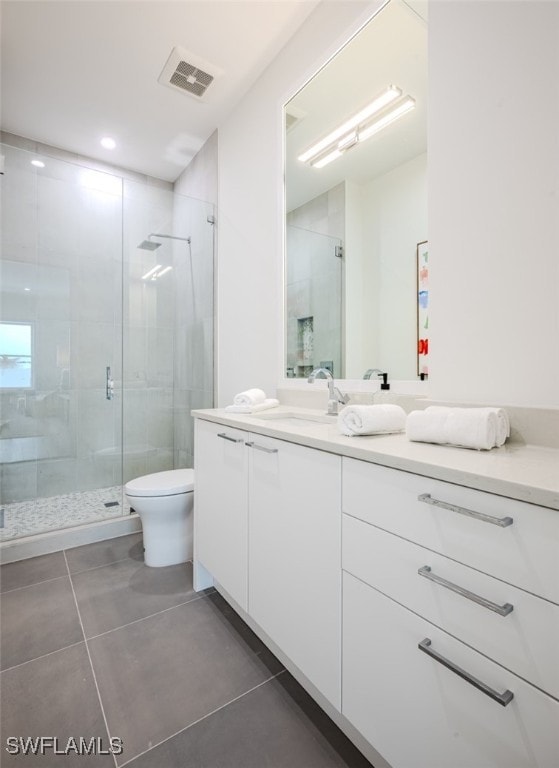 bathroom featuring tile patterned flooring, a shower with door, vanity, and toilet