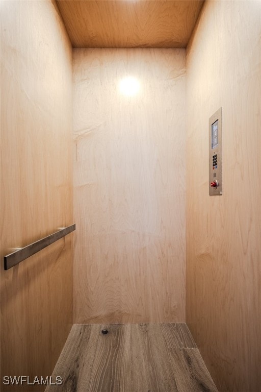 interior space featuring wooden ceiling, wood walls, and elevator