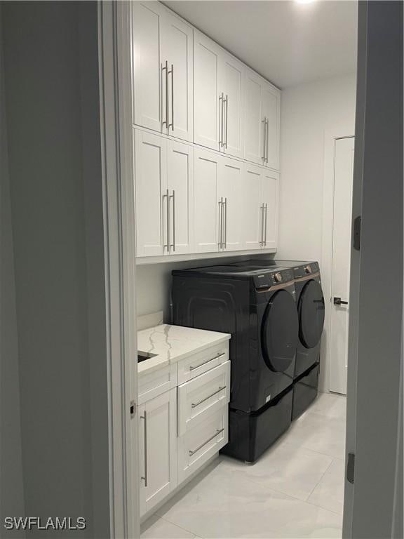 clothes washing area with cabinet space and independent washer and dryer