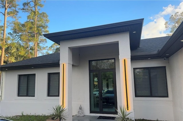 doorway to property featuring a shingled roof and stucco siding