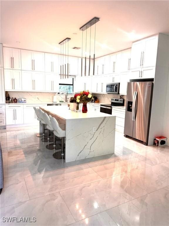 kitchen featuring appliances with stainless steel finishes, a kitchen island, and white cabinets