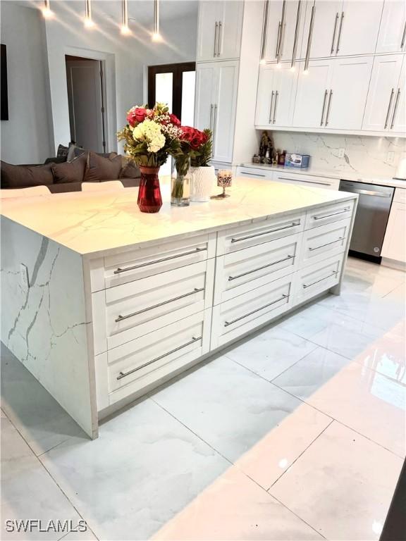 kitchen with light stone counters, open floor plan, marble finish floor, white cabinetry, and stainless steel dishwasher