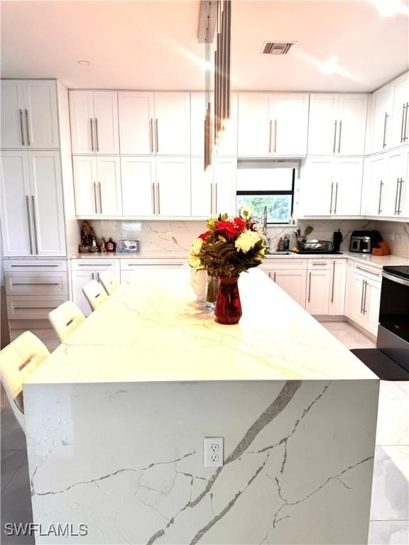 kitchen featuring light stone counters, white cabinetry, visible vents, electric stove, and tasteful backsplash