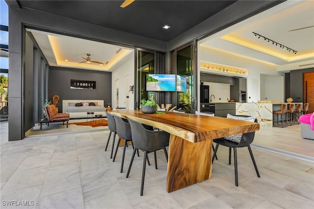 interior space featuring track lighting, ceiling fan, and a tray ceiling