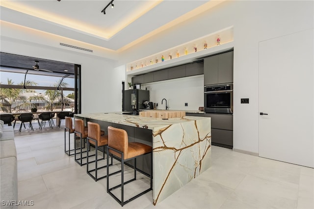 kitchen featuring black fridge, a breakfast bar, oven, and a raised ceiling