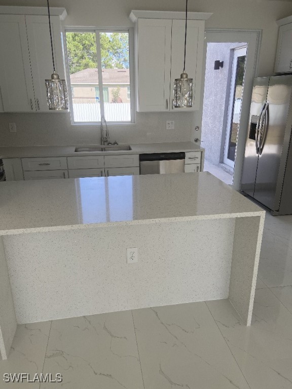 kitchen featuring appliances with stainless steel finishes, sink, pendant lighting, and white cabinets