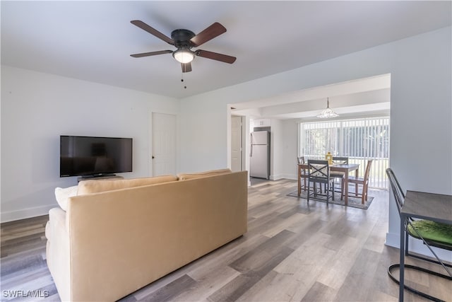 living room featuring hardwood / wood-style floors and ceiling fan with notable chandelier