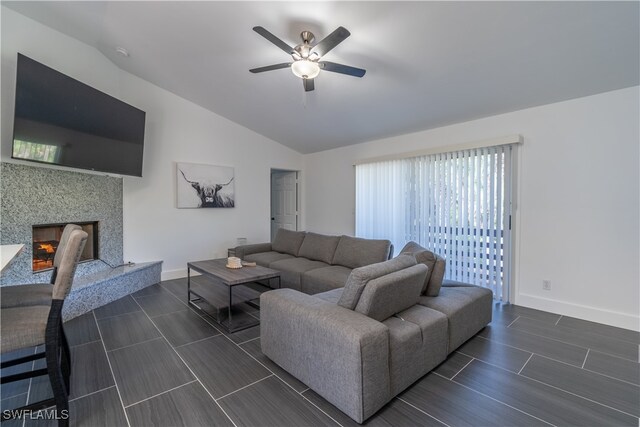 living room with a premium fireplace, dark hardwood / wood-style flooring, lofted ceiling, and ceiling fan