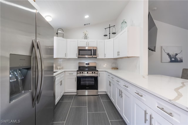 kitchen with vaulted ceiling, white cabinetry, and appliances with stainless steel finishes