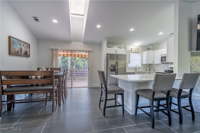 kitchen with white cabinets, sink, a breakfast bar, and appliances with stainless steel finishes