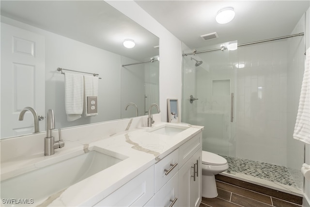 bathroom with toilet, vanity, and a shower with door