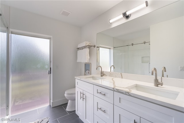 bathroom with toilet, vanity, and a shower with shower door