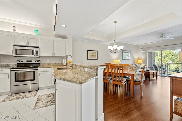 kitchen featuring sink, decorative light fixtures, white cabinetry, stainless steel appliances, and ceiling fan with notable chandelier