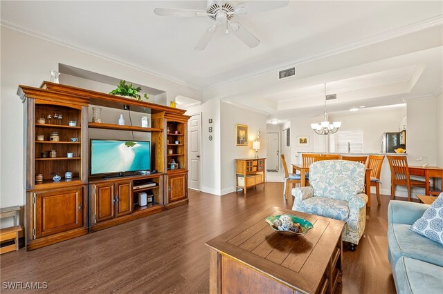 living room with ceiling fan with notable chandelier, dark hardwood / wood-style floors, a tray ceiling, and crown molding