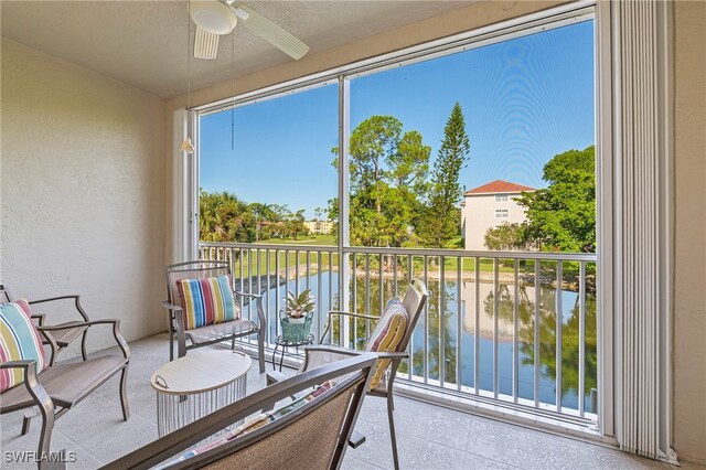 sunroom featuring a water view, ceiling fan, and a wealth of natural light