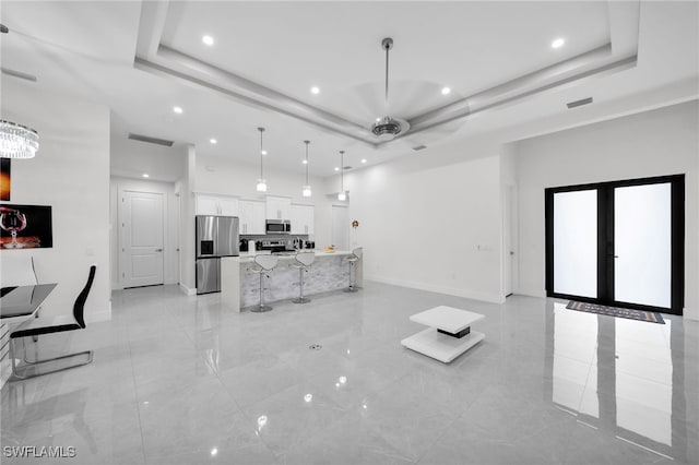 unfurnished living room featuring ceiling fan, a tray ceiling, and french doors