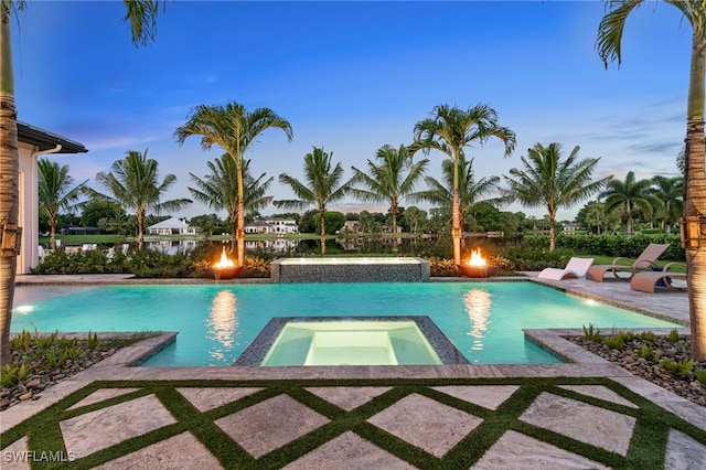 pool at dusk with an in ground hot tub